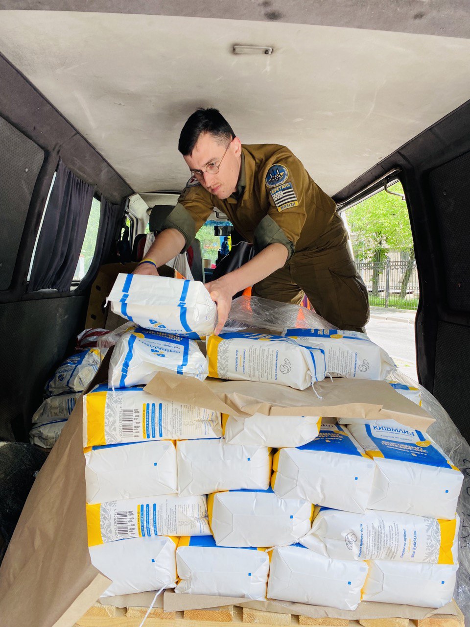 A volunteer loading sacks of flour into a delivery van