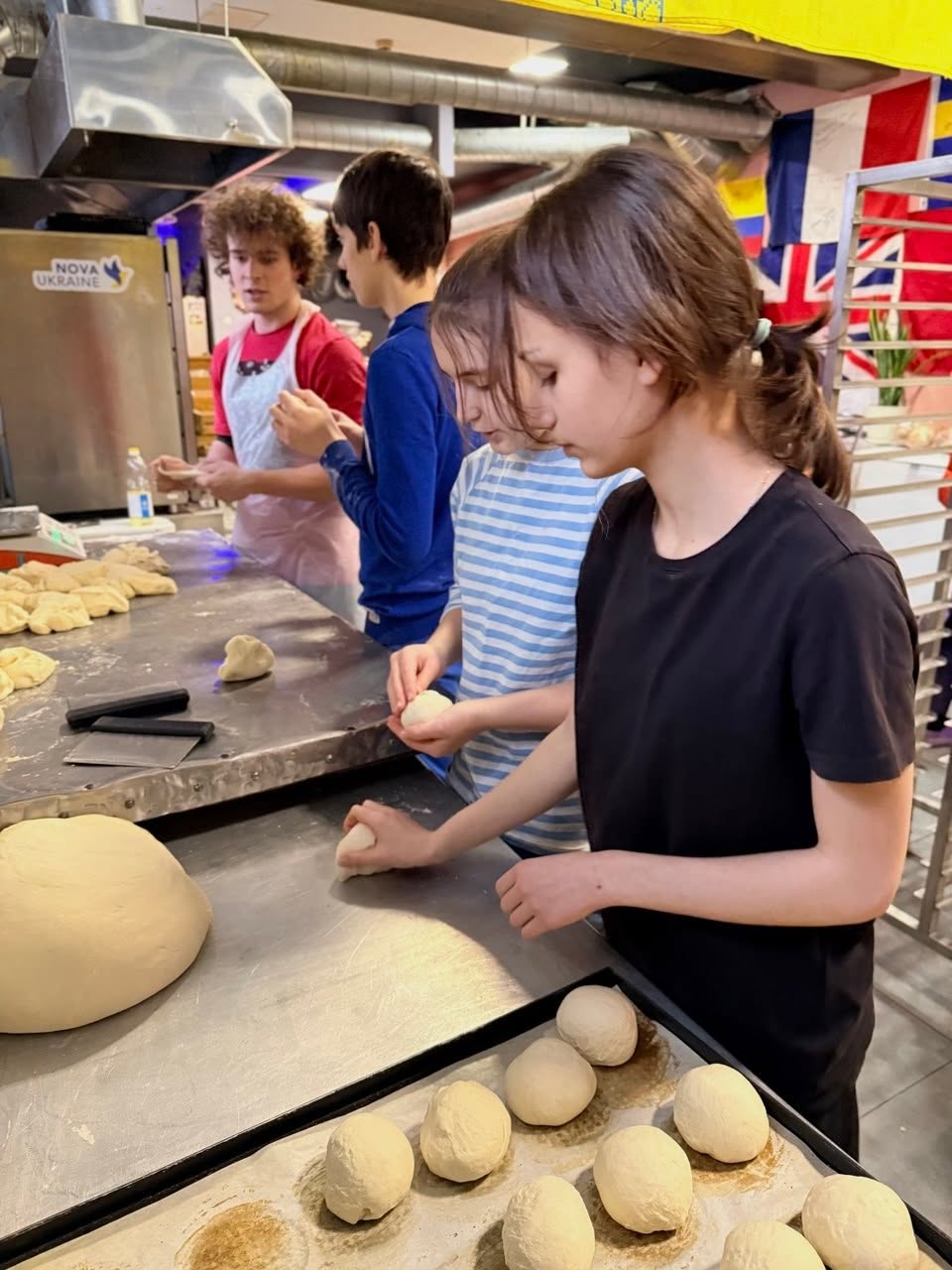 Young volunteers rolling dough into bread rolls